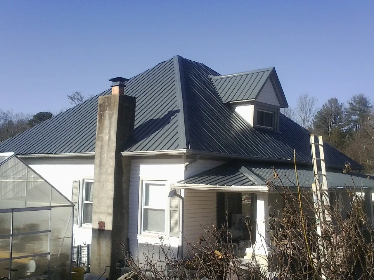 Dark blue standing seam metal roof on a white farmhouse with dormer — Slate & Tile Roof Repair by Roofing Brothers in Watsonville