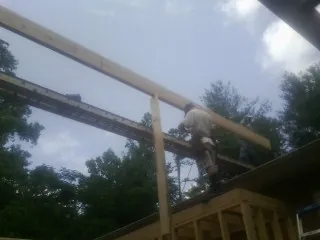Carpenter setting a ridge beam over a new addition frame — Ice Dam Removal by Roofing Brothers in Watsonville
