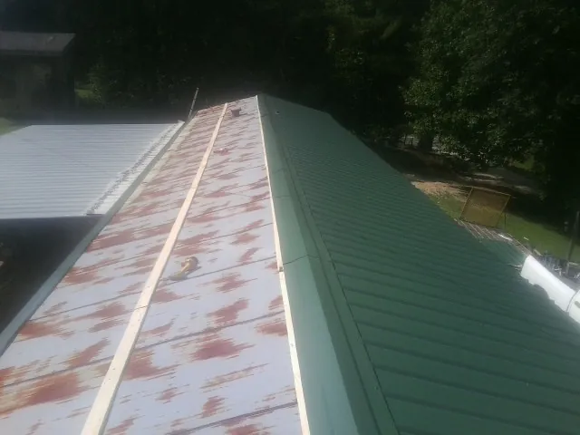 Old rusted panels beside newly installed green metal roofing — Wind Damage Roof Repair by Roofing Brothers in Watsonville
