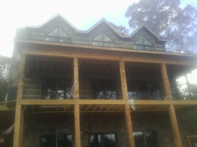 Dormers and porch framing on a large log home under construction — Roof Coating work by our crew in Watsonville