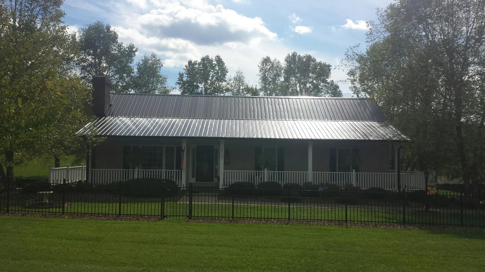 Gray metal roof on a brick ranch with a full width front porch — Gutter Guard Installation work by our crew in Watsonville