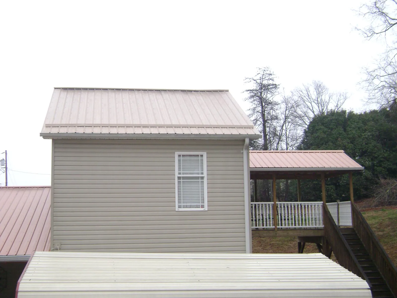 Tan metal roofs on a two story addition and attached porch, from a Roof Replacement job in Watsonville