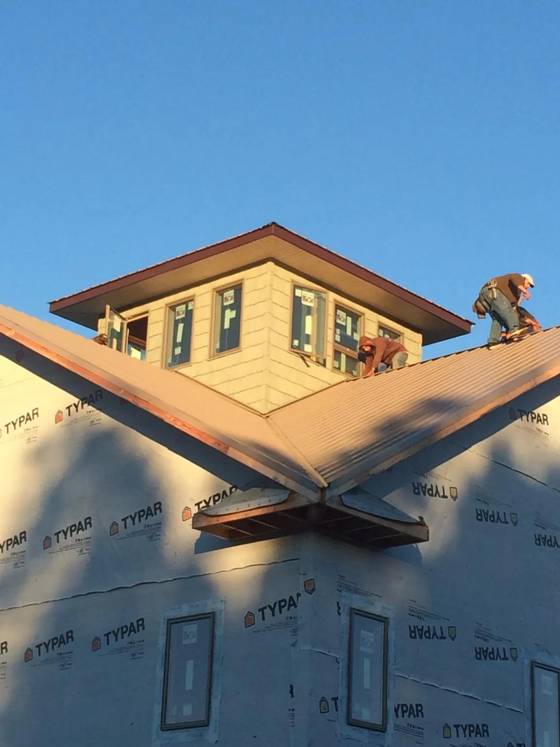 Roofers working around a rooftop cupola on a new metal roof at sunset — Roof Waterproofing in Watsonville by Roofing Brothers